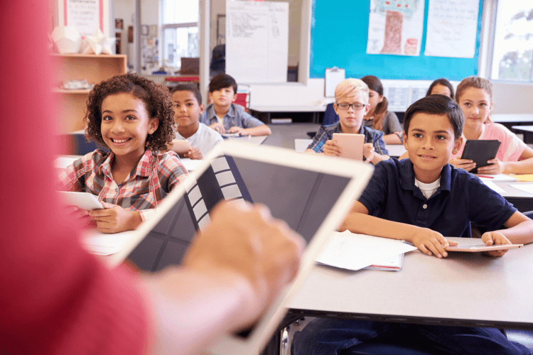 teachers hand , tablet device , learners inside the classroom