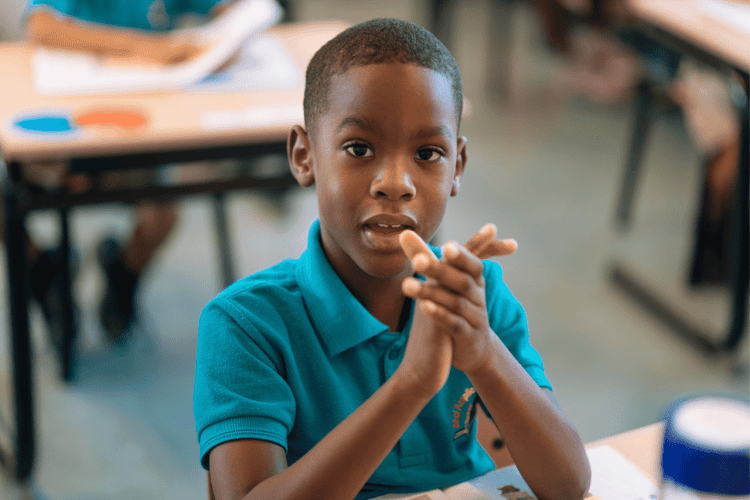 a boy putting hands together inside the classroom
