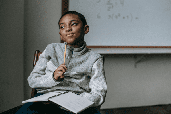 How AI Can Help Close the Education Gap in South Africa a boy in the classroom , using a pencil pointing on his chin , open book