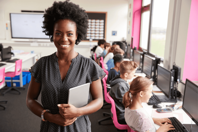 class teacher standing , learners facing their computer screens and typing
